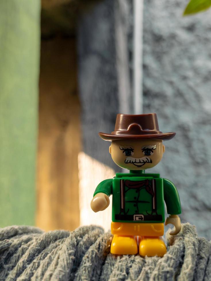 October 2022, Jakarta Indonesia, minifigure toy against a background of a blurred wall and a wooden fence in the sun photo