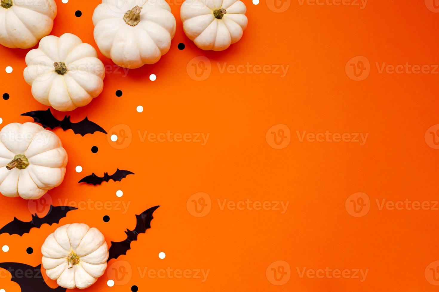 Halloween flat lay composition of black paper bats fand pumpkins on orange background. Halloween concept. photo