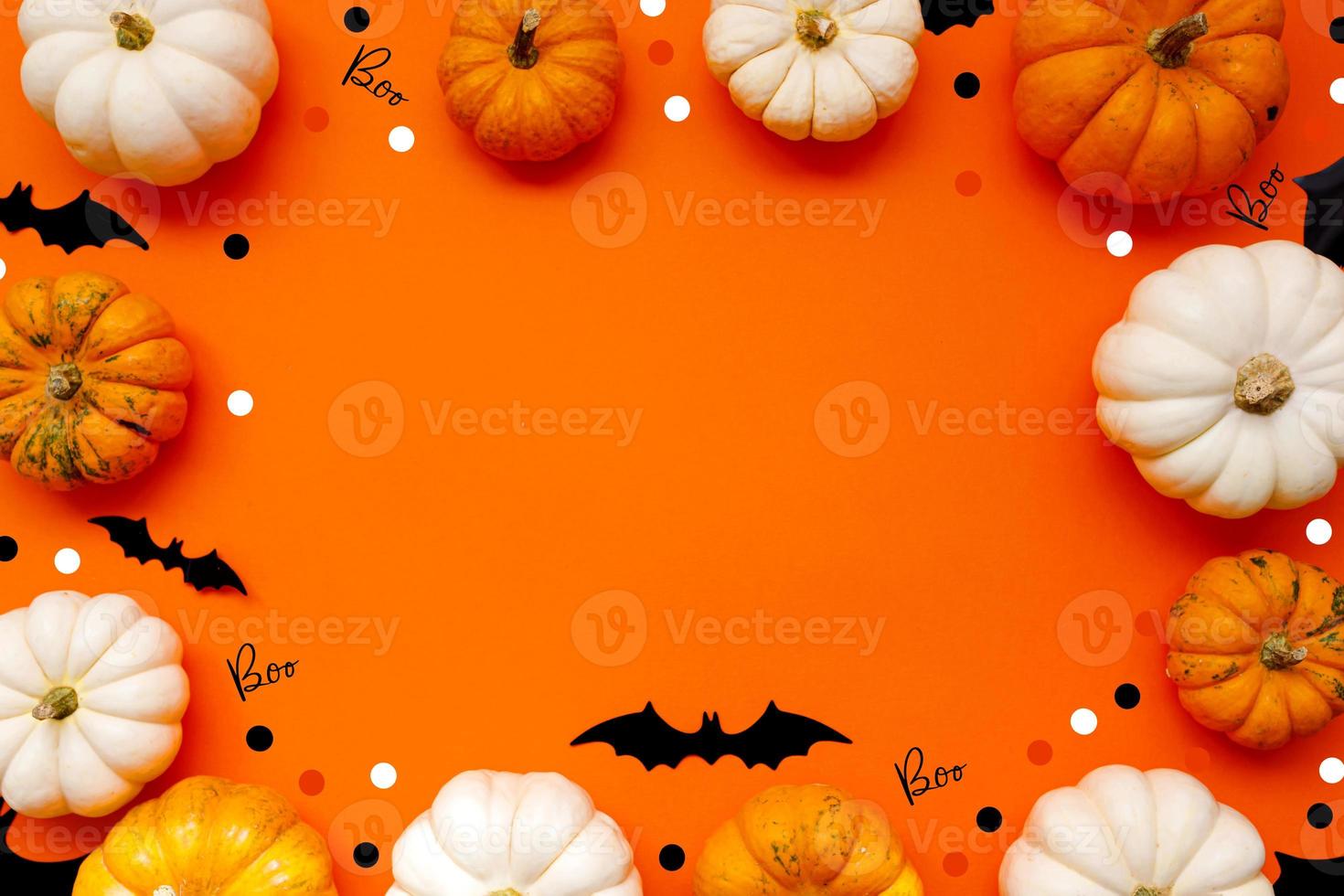 Halloween flat lay composition of black paper bats fand pumpkins on orange background. Halloween concept. photo