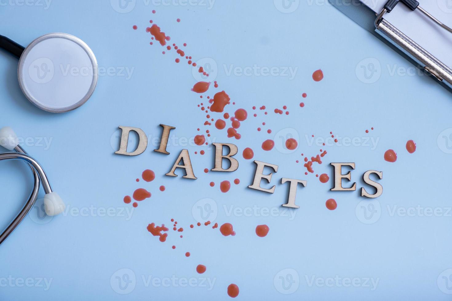 palabra diabetes con gotas de sangre, un estetoscopio sobre un fondo azul foto