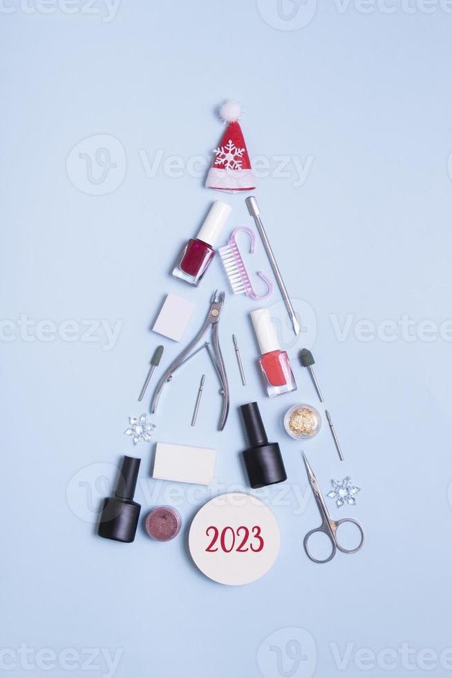 Manicure tools and nail polishes are laid out in the shape of a Christmas tree. 2023 numbers of new year photo