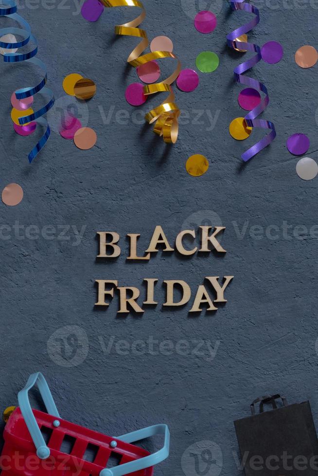 Black Friday text with holiday tinsel flat lay on dark background. Black Friday sale concept vertical photo