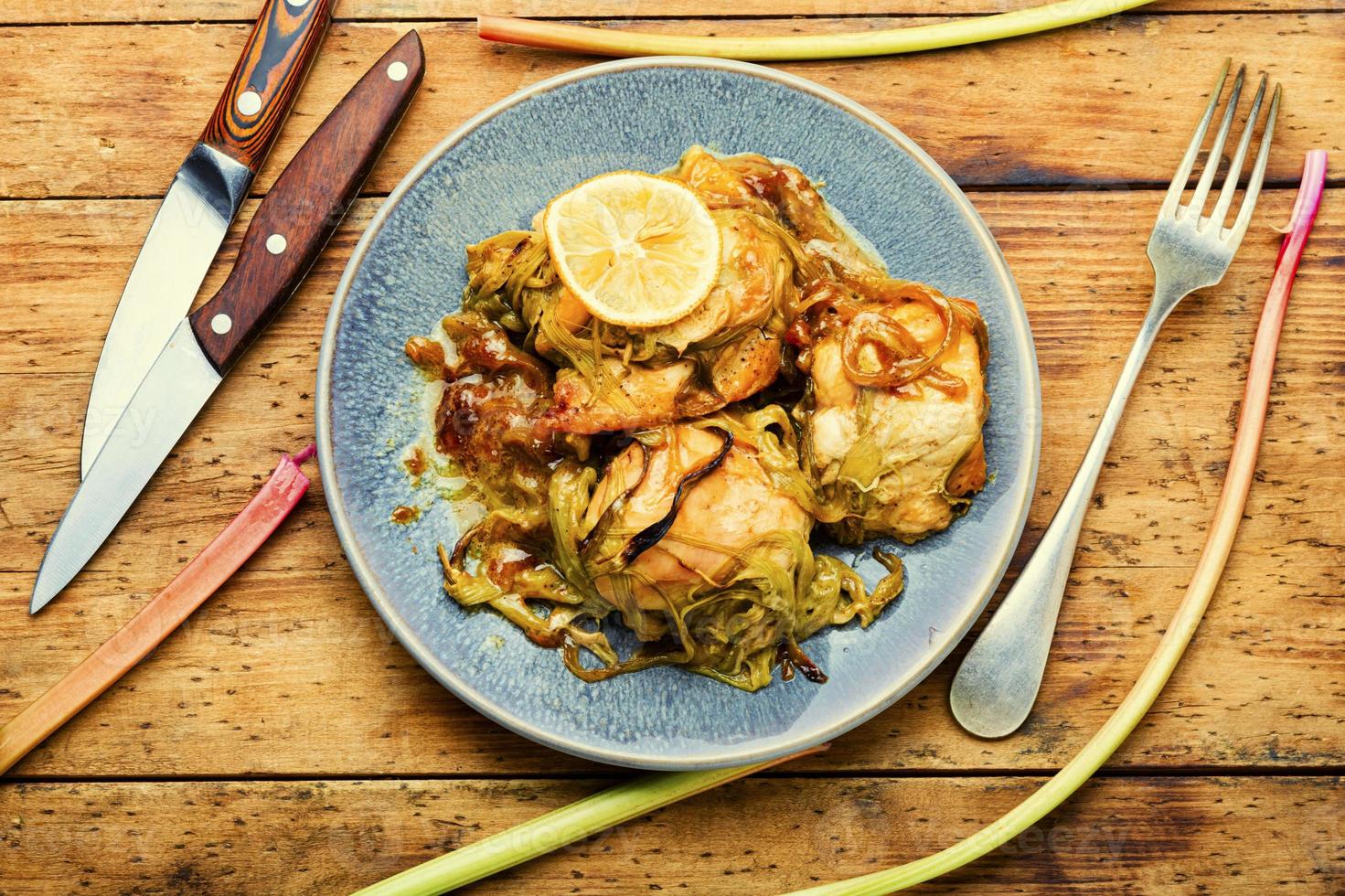Chicken meat baked with rhubarb,wooden table photo