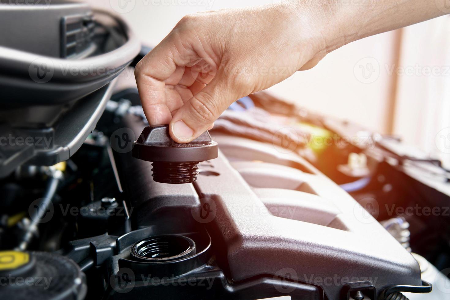 entregue a un hombre la tapa del aceite del motor en la sala del motor para verificar y agregar aceite del motor al automóvil del motor foto