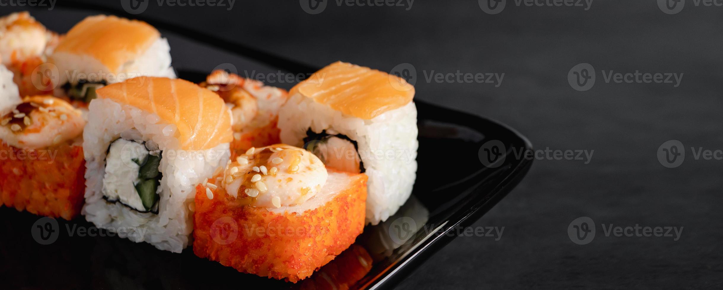 Set of Philadelphia sushi rolls on black plate. Serving Japanese food in restaurant. photo