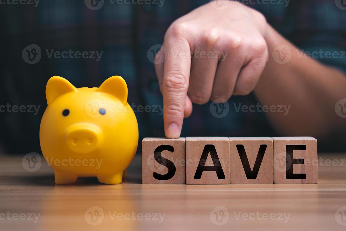 saving money. Man's hand pointing to saving money on a wooden block on a wooden table, money saving wealth and financial concepts business finance investing financial planning photo