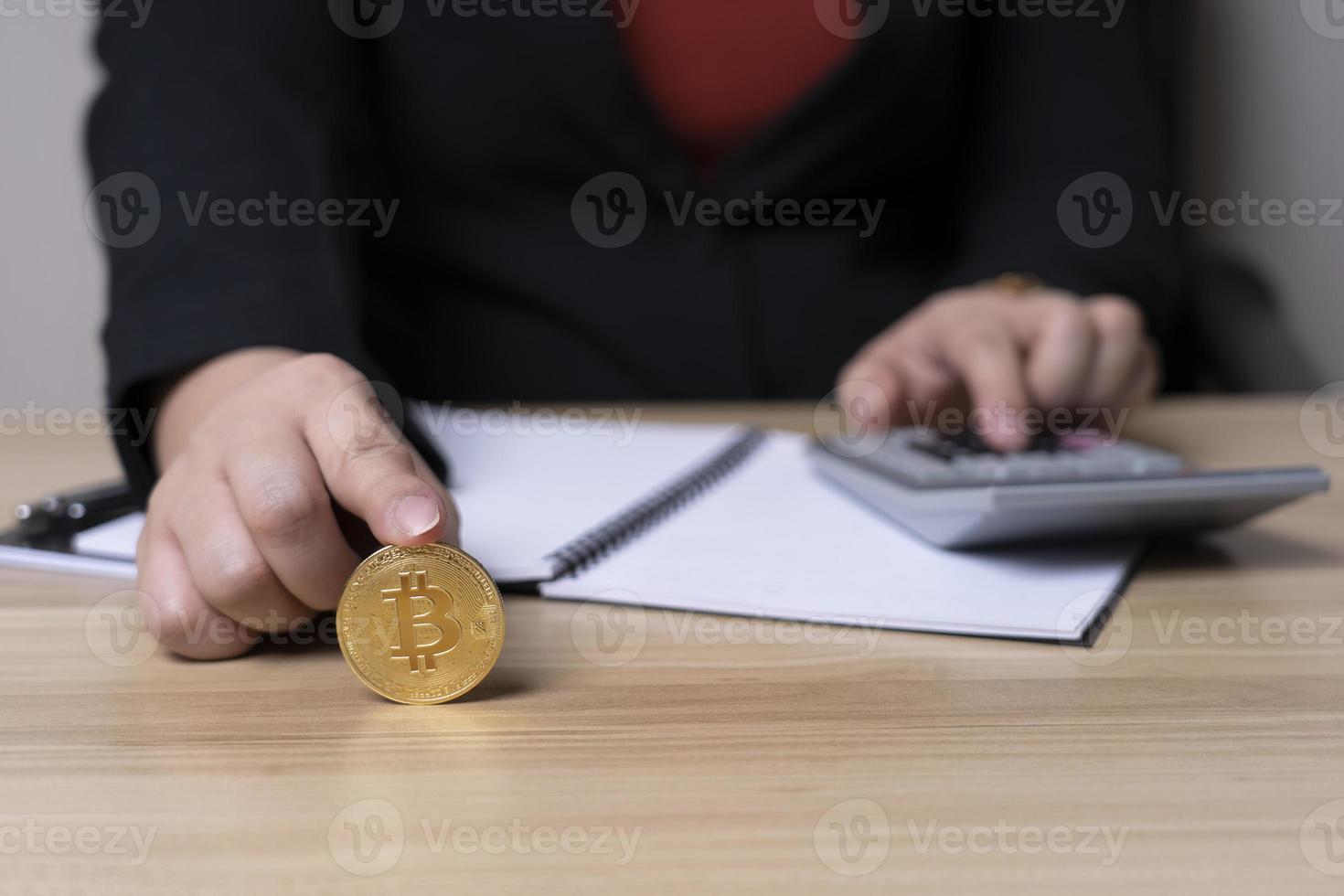 businesswoman finger touching bitcoin coin and is calculating investment income with a calculator on the desk with graph chart. digital. finance, investor, collect money, investment risk photo