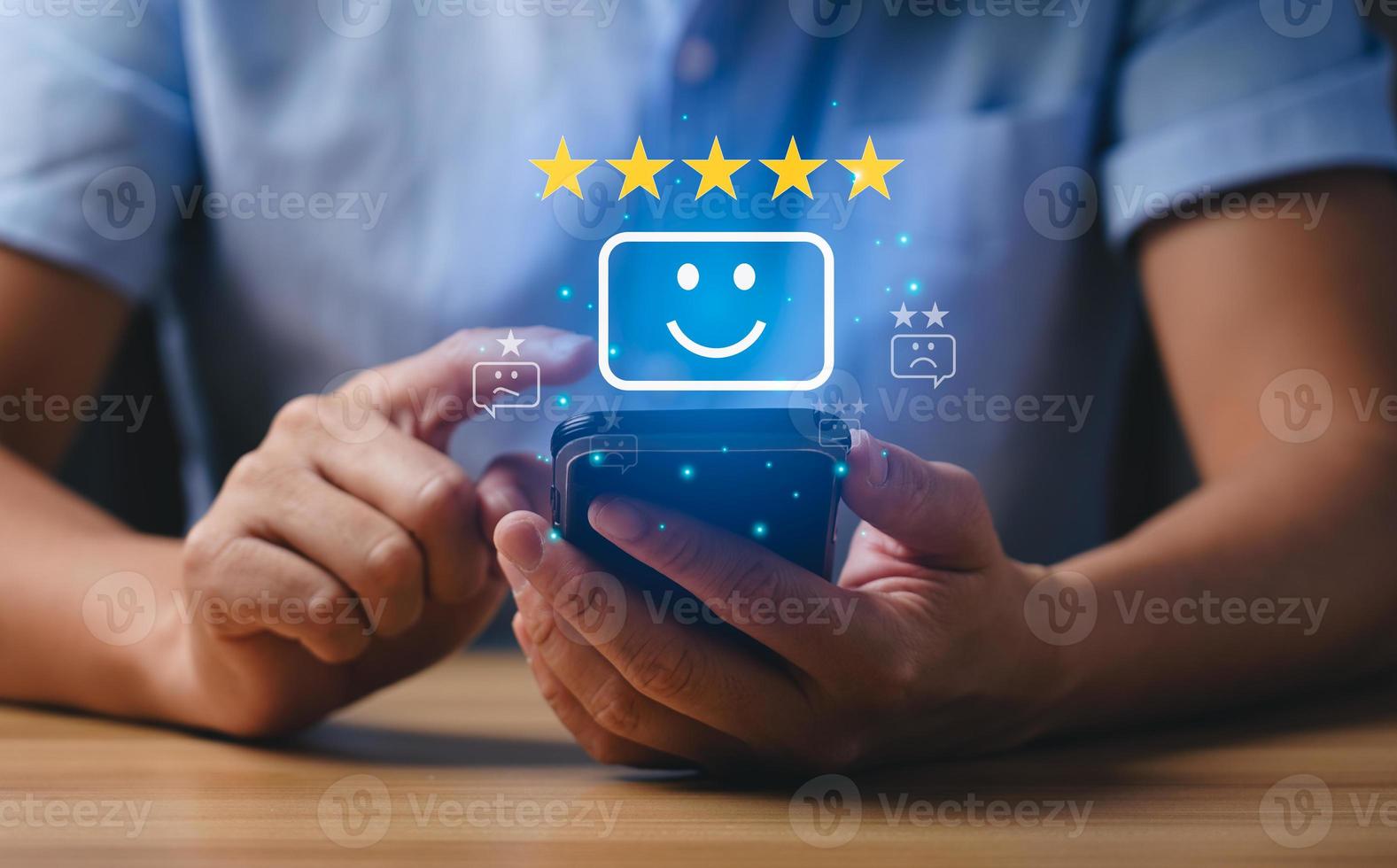 concepto de satisfacción del cliente y del consumidor. los hombres de negocios o los clientes expresan su satisfacción a través de una aplicación en la pantalla de un teléfono inteligente para elegir una calificación de 5 estrellas y un emoji de cara sonriente foto