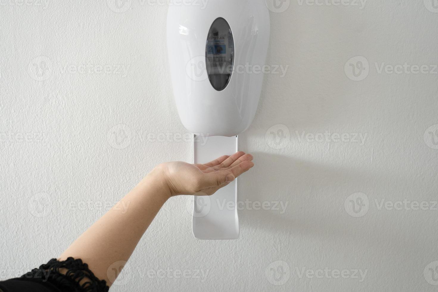 woman's hand using alcohol gel with automatic machine in the hospital for cleaning hands. Economical and clean infection prevention concept in the state medical center area. disinfection photo