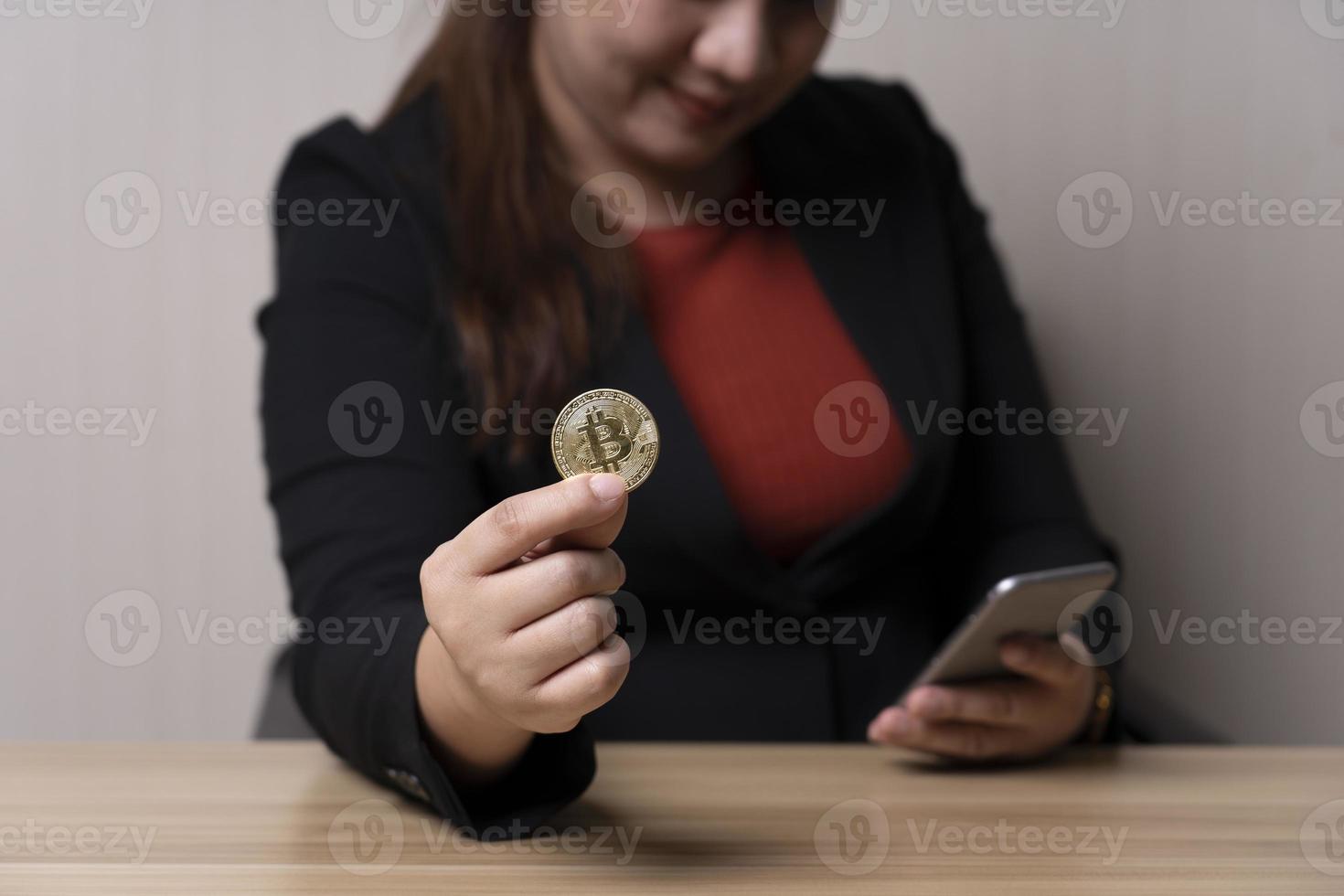 business woman holding bitcoins and trades cryptocurrency on her smartphone. concept cryptocurrency exchange. technology and investment digital. finance, investor, collect money, high investment risk photo