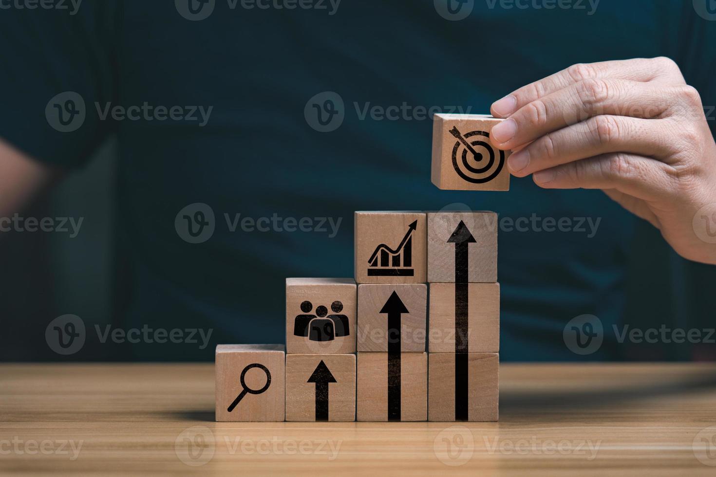 Businessman's hand selects a target icons on wooden cubes, business development concept. business strategy and action plan, goals for success, management photo