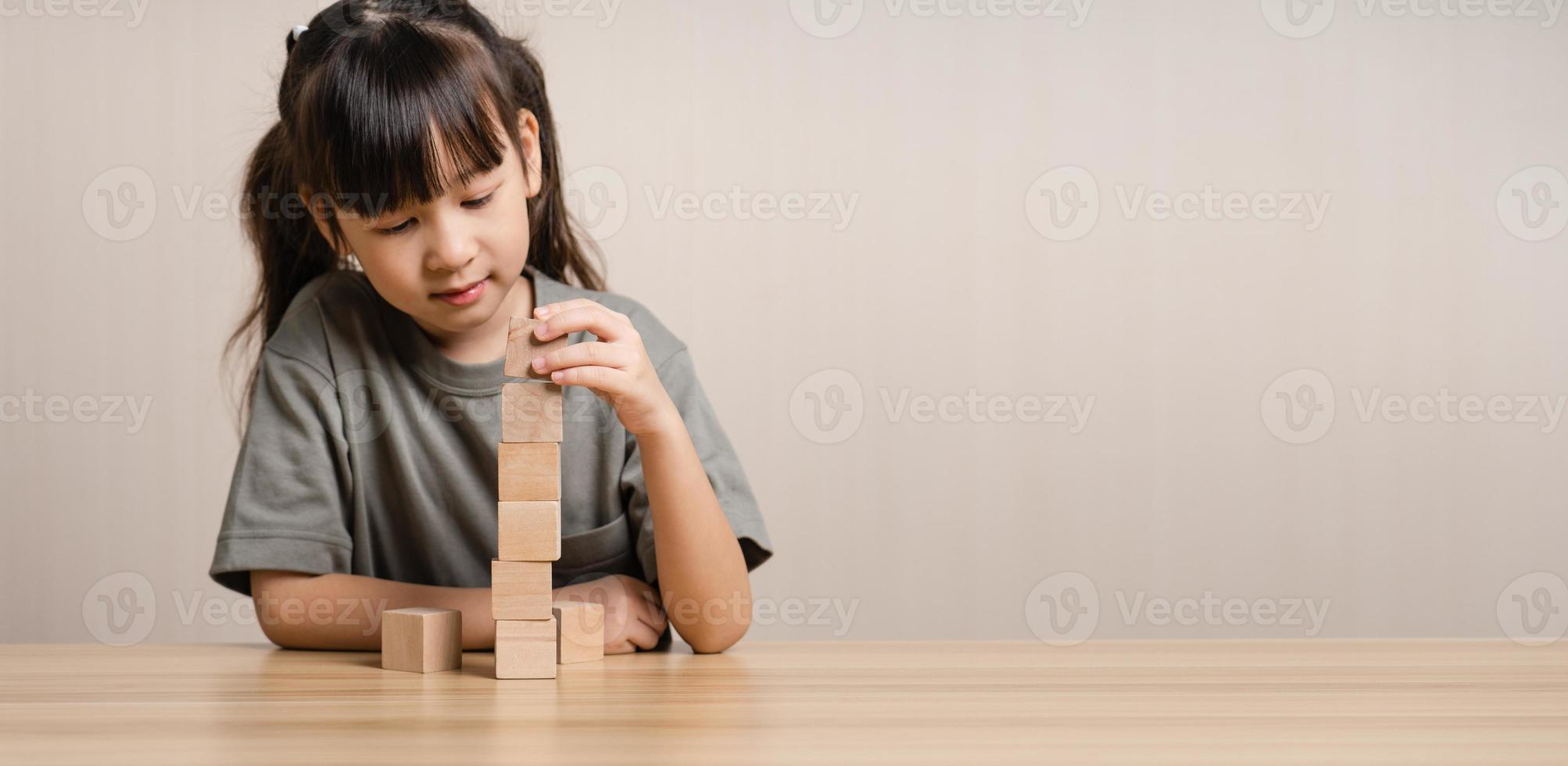 Girls build wooden cubes in layers with wooden blocks cube wooden box. girl playing with wooden block toys. Concept of early child development photo