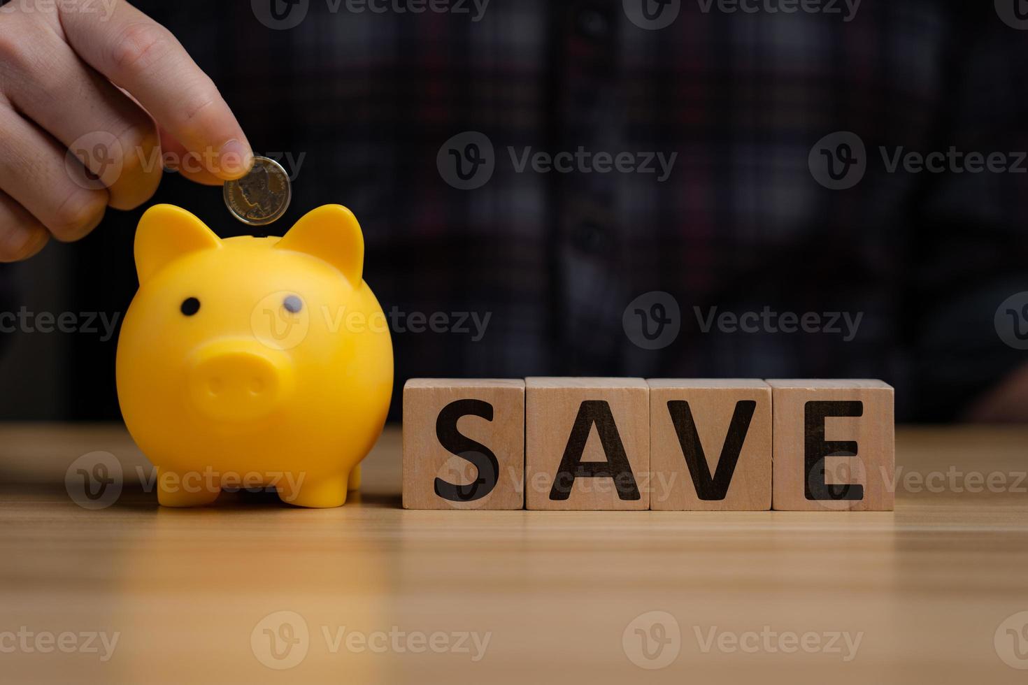 Man's hand holding money in a piggy bank on a wooden table, money saving wealth and financial concepts business finance investing financial planning photo