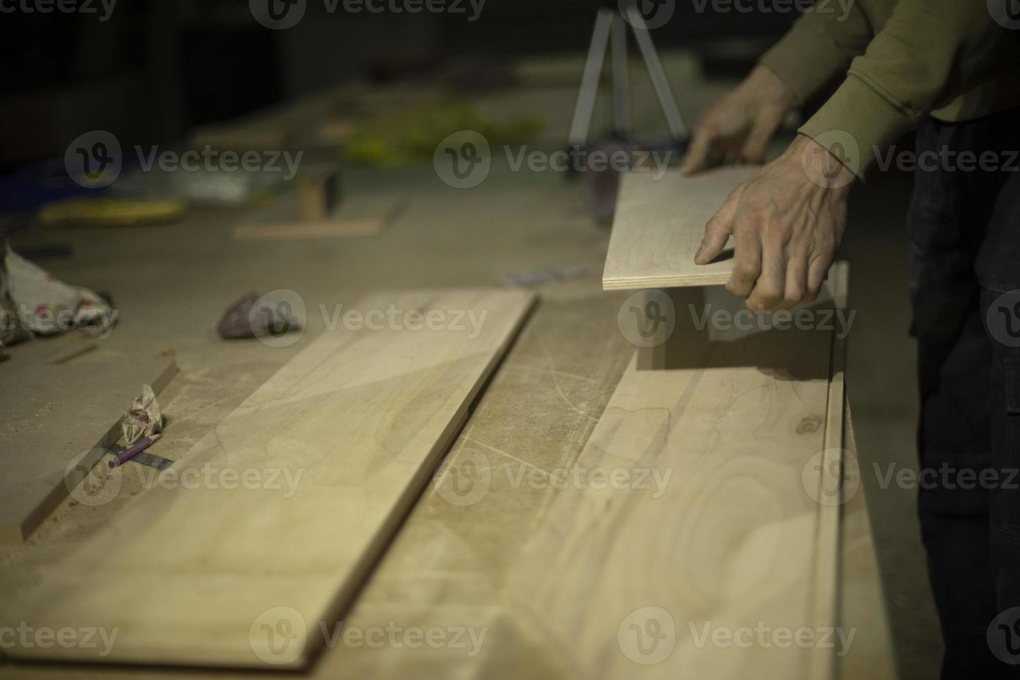 Carpenter holds tree. Worker chooses board. Details of carpentry workshop. photo