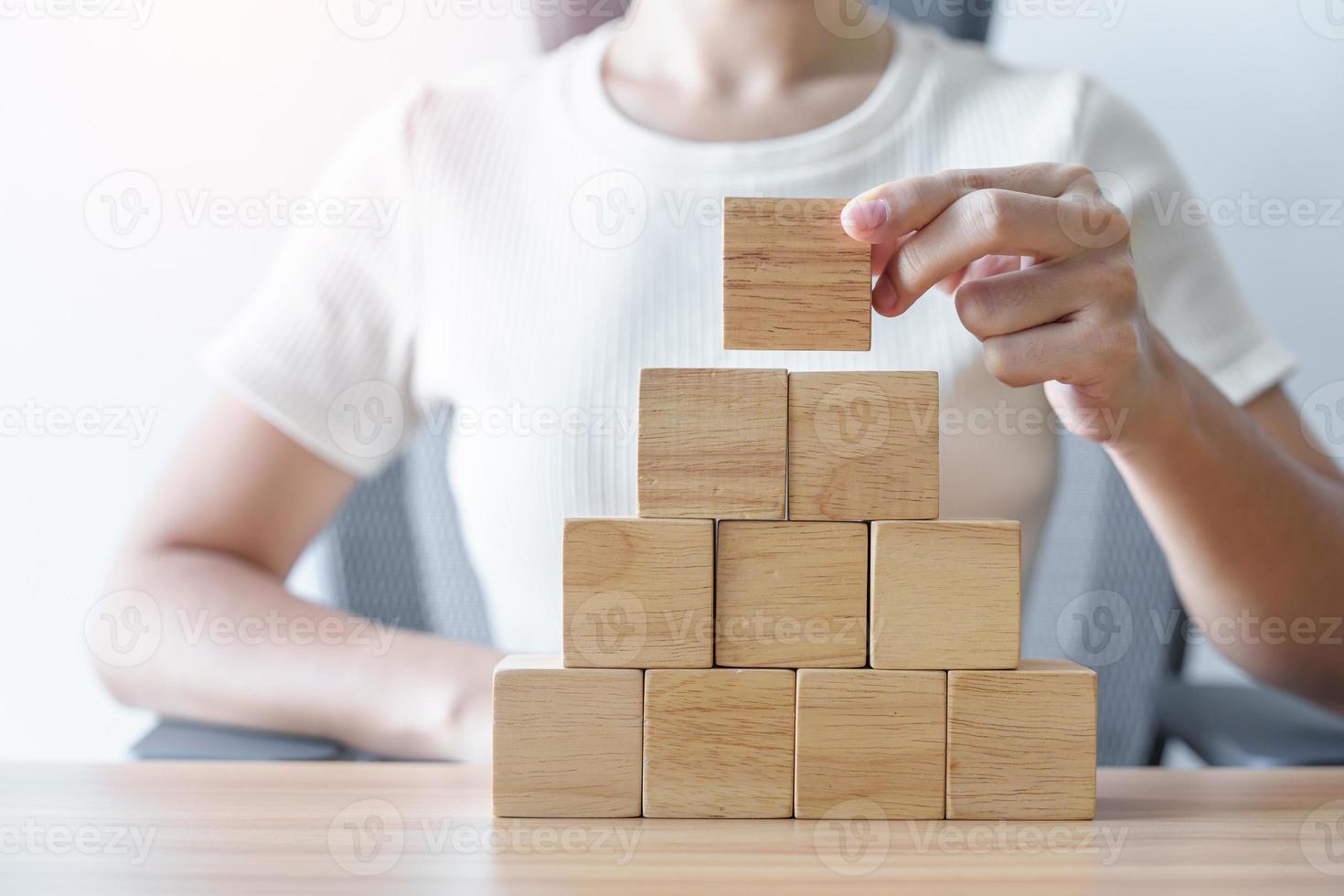 Woman hand placing wood block on the building. Leadership, Business process planning, Risk Management and strategy Concepts photo