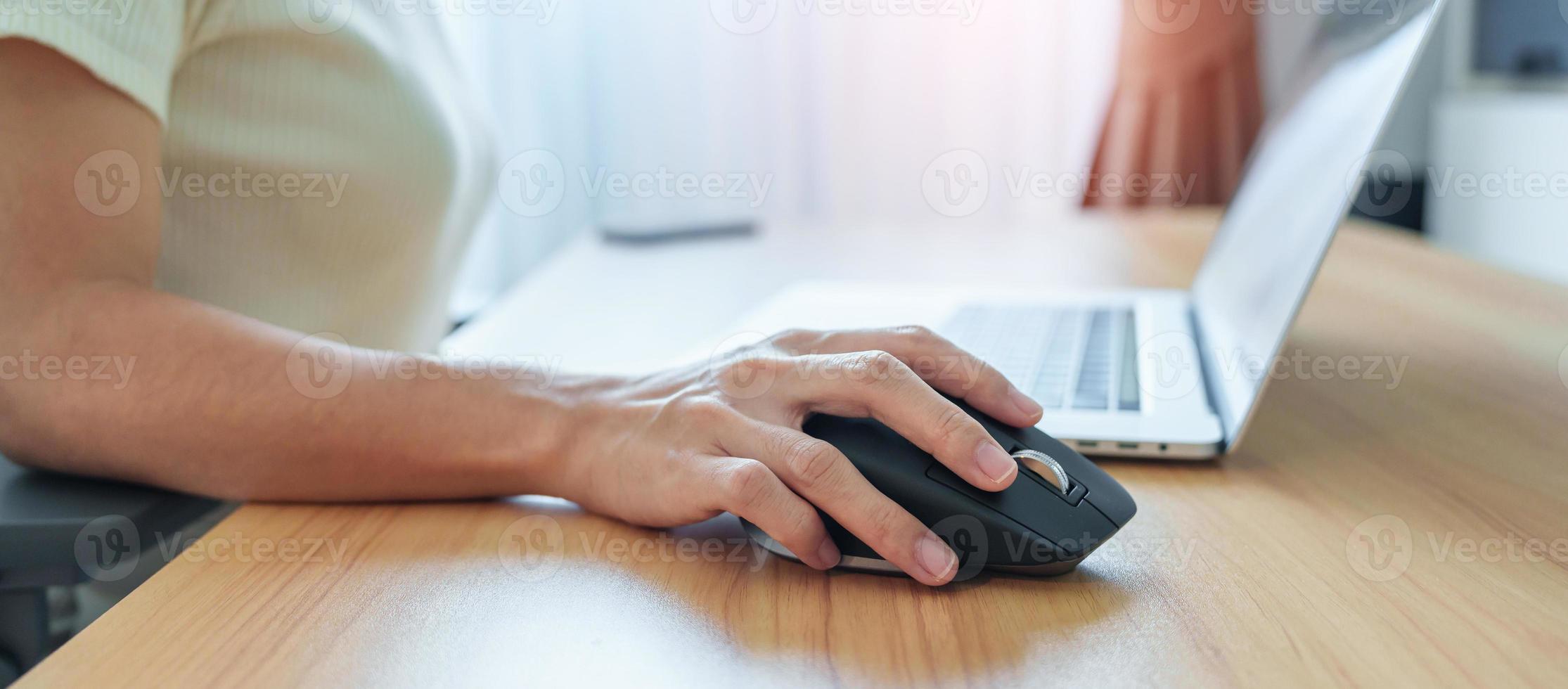 woman hand using ergonomic vertical mouse during working on Adjustable desk, prevention wrist pain. De Quervain s tenosynovitis, Intersection Symptom, Carpal Tunnel or Office syndrome concept photo