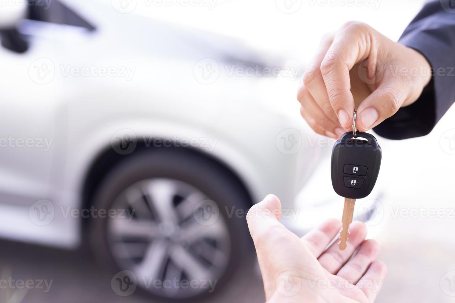 Salesman is carrying the car keys delivered to the customer at the showroom with a low interest offer. Special promotion photo