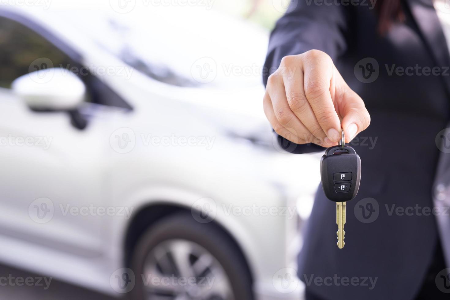 Salesman is carrying the car keys delivered to the customer at the showroom with a low interest offer. Special promotion photo