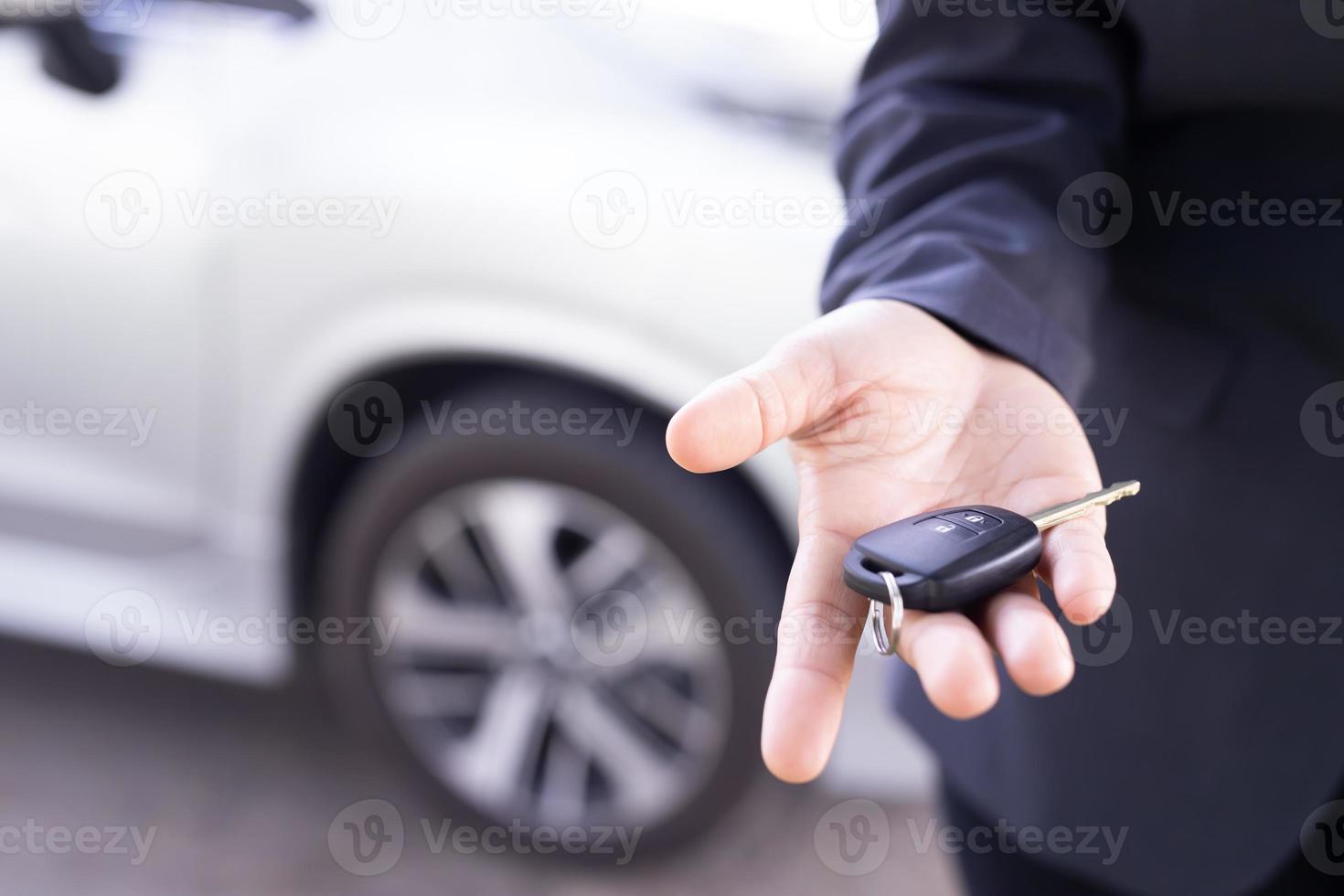 Salesman is carrying the car keys delivered to the customer at the showroom with a low interest offer. Special promotion photo