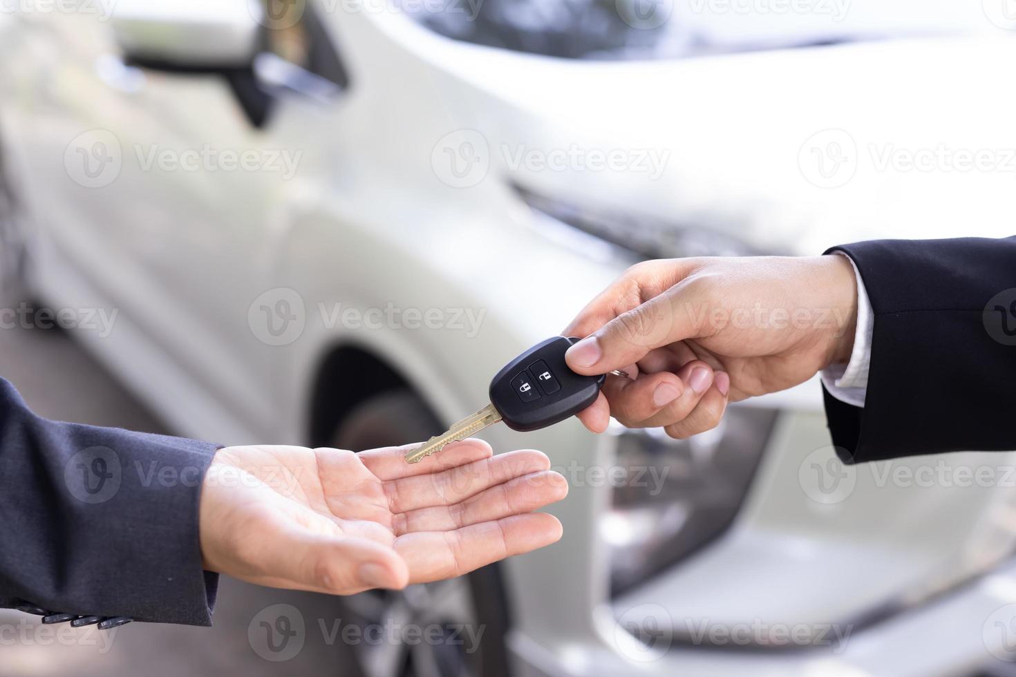 Salesman is carrying the car keys delivered to the customer at the showroom with a low interest offer. Special promotion photo