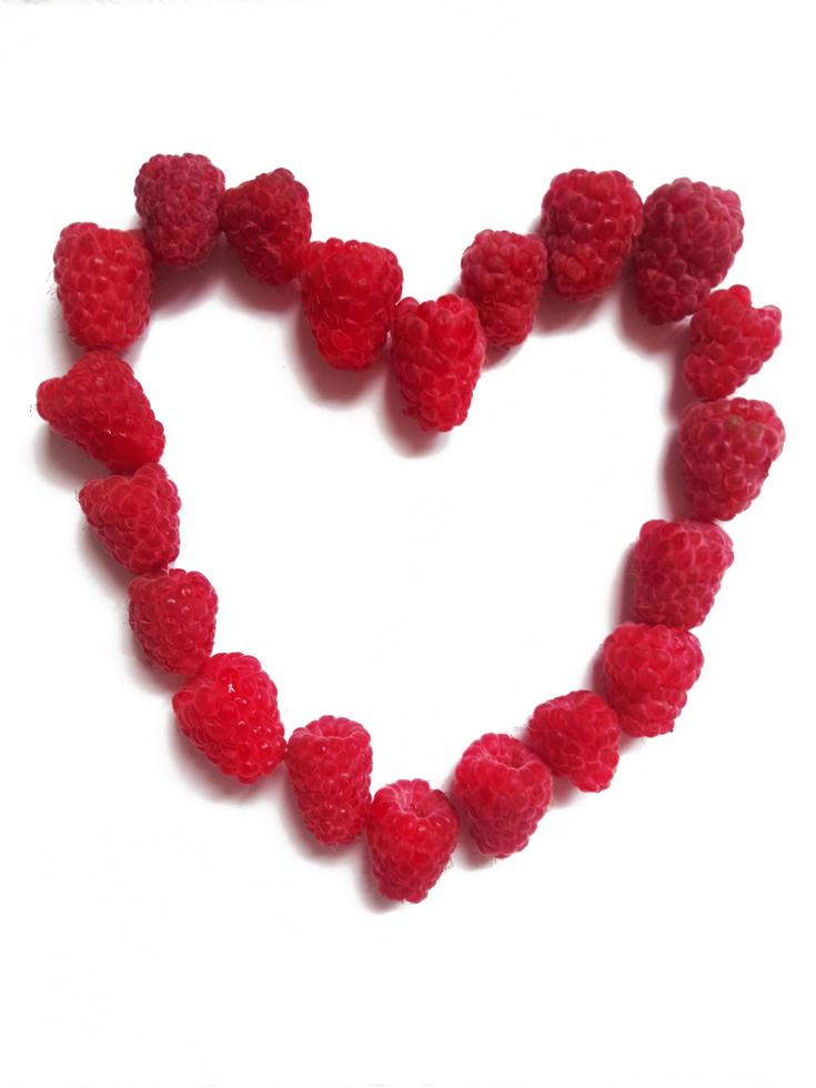 raspberry heart. The figure of the heart is lined with ripe raspberry berries on a white background. photo