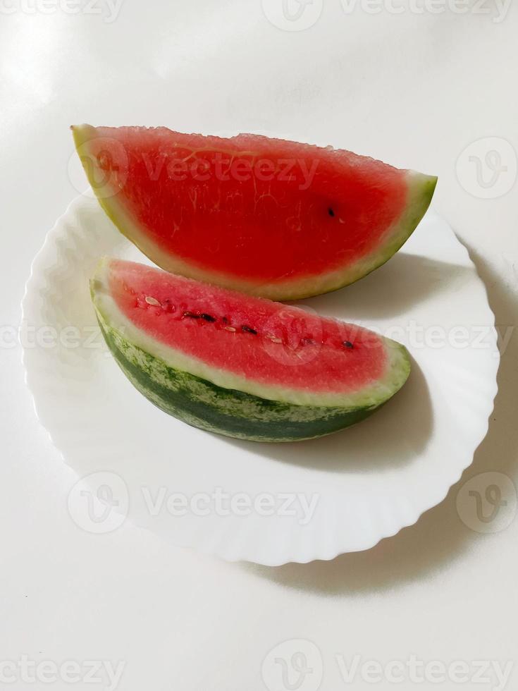 sandía en rodajas en un plato sobre un fondo blanco foto