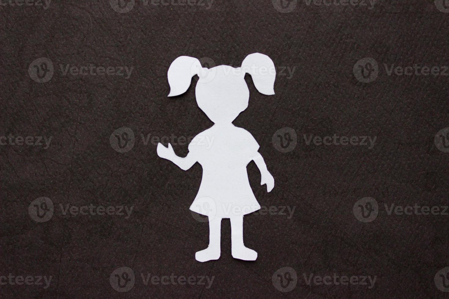 The form of a girl in a dress and with ponytails made of white paper, cut by hand. photo