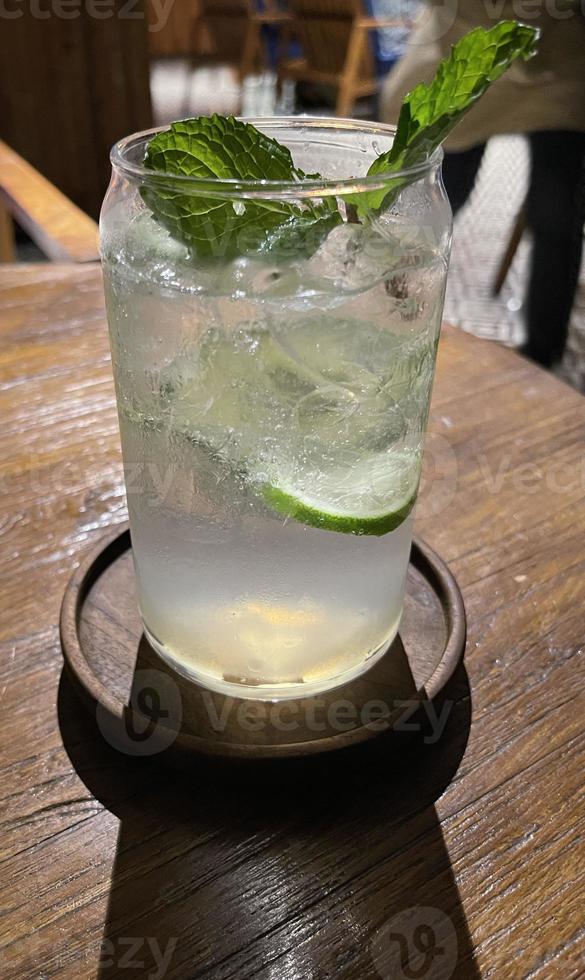 Selective focus, Delicious refreshing summer mojito with ice, lime and mint in a glass with grops. wood background photo