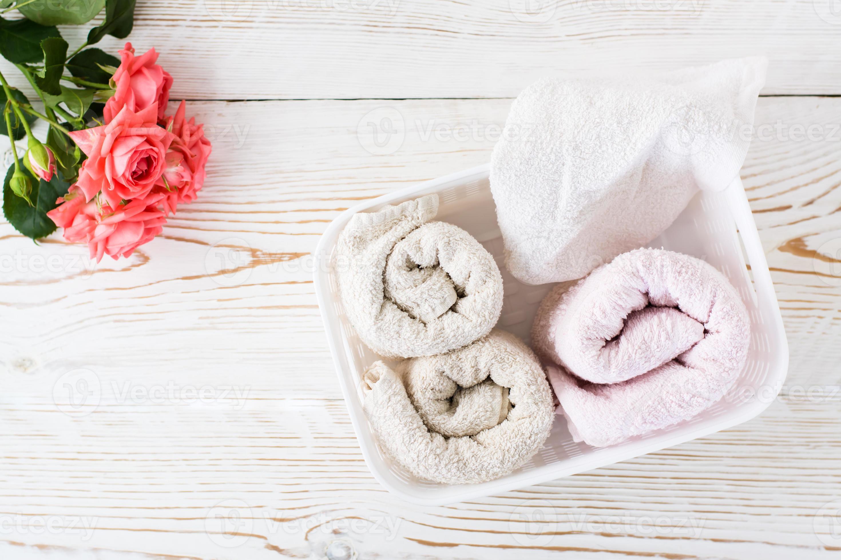 Rolled clean towels in a container and a bouquet of roses. Top