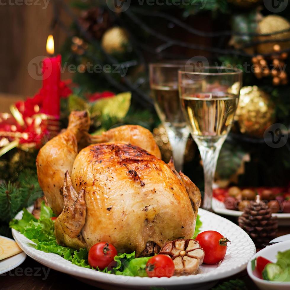 Baked turkey or chicken. The Christmas table is served with a turkey, decorated with bright tinsel and candles. Fried chicken, table. Christmas dinner. photo