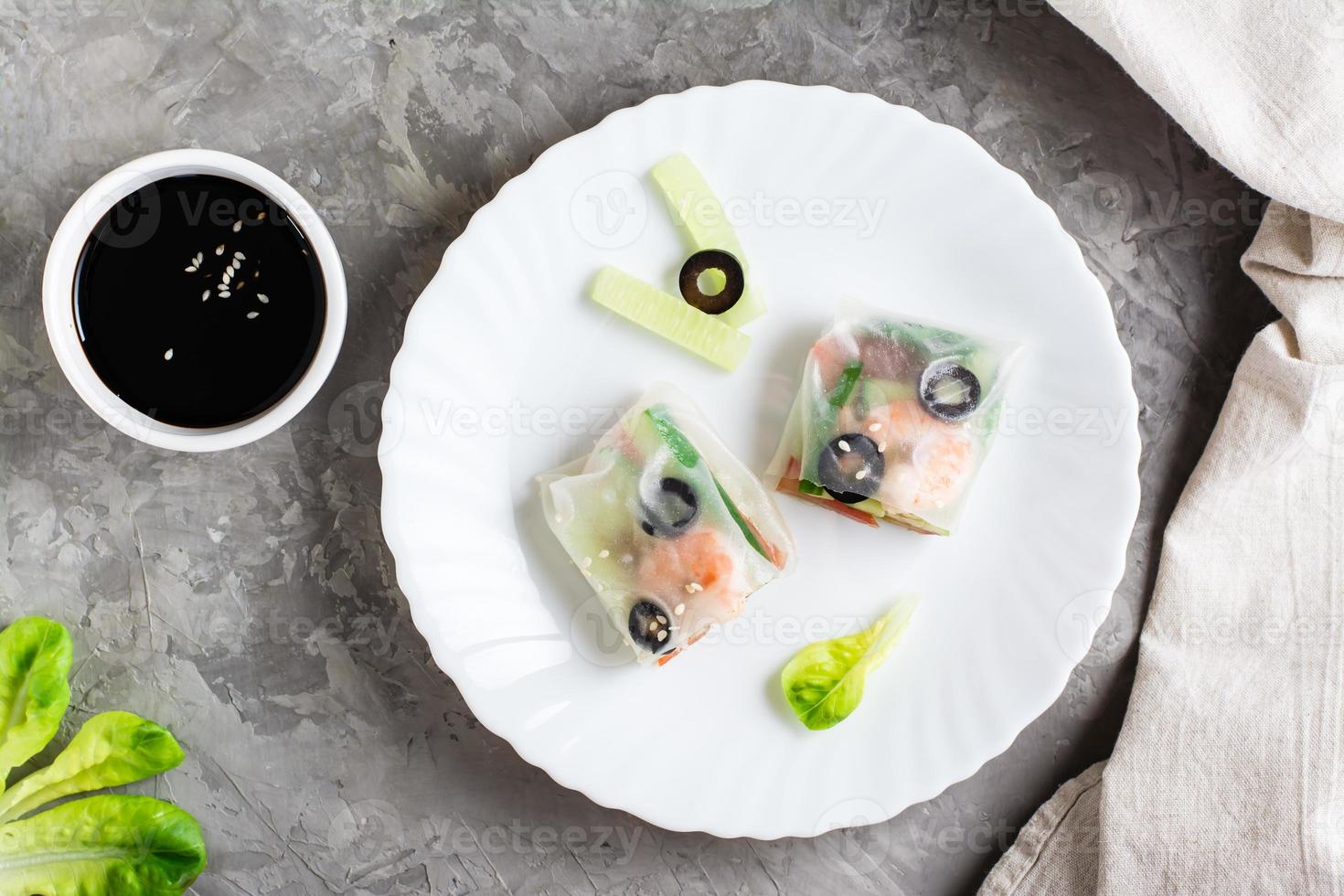 Spring roll cut in half in rice paper with seafood and vegetables on a plate. Top view. Close-up photo
