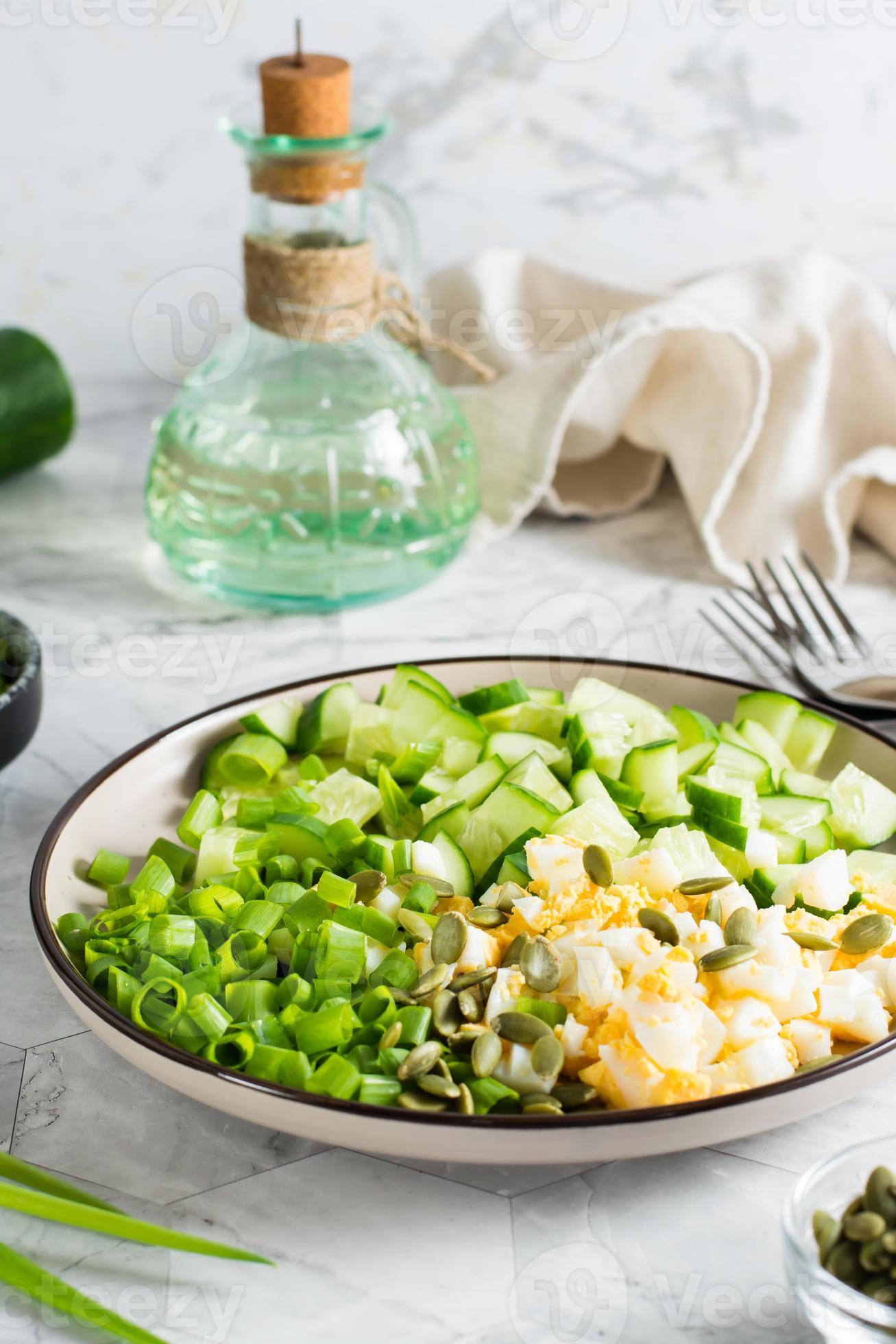 Salad of cucumber, boiled egg and green onion on a plate. Ketogenic diet. Vertical view. Close