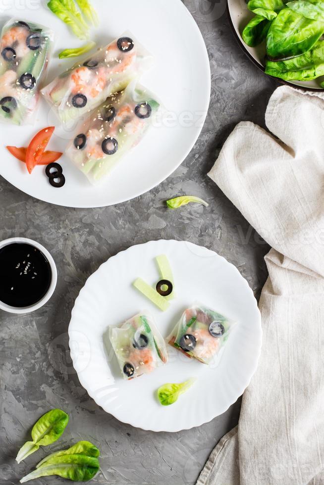 Spring roll cut in half in rice paper with seafood and vegetables on a plate. Top an vertical view. photo