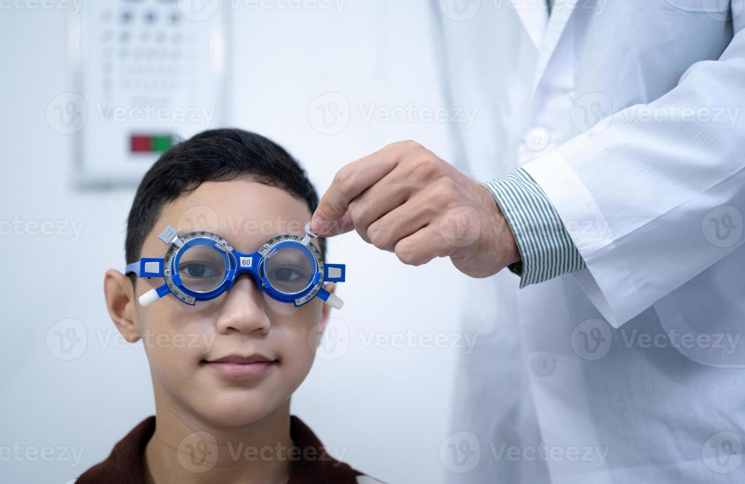 Boy has his eyes checked for glasses by a specialist. photo