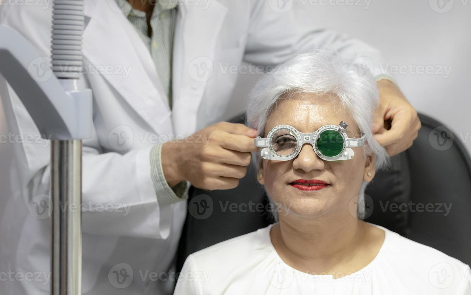 Ophthalmologist measures eyesight for an elderly woman. photo