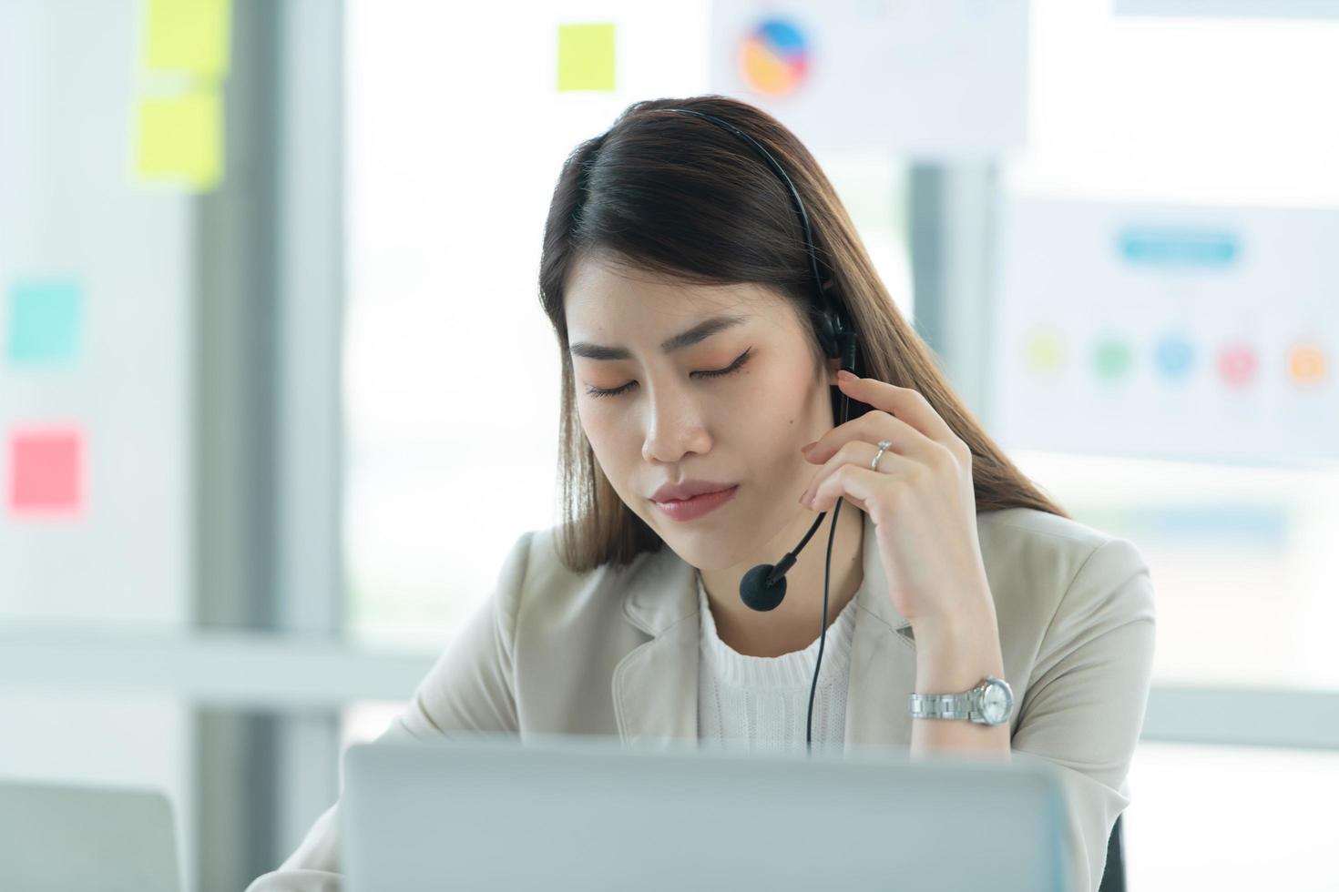 Young asian woman working at a call center Consulting about stock investment information with customers calling for advice with emotion of serious photo