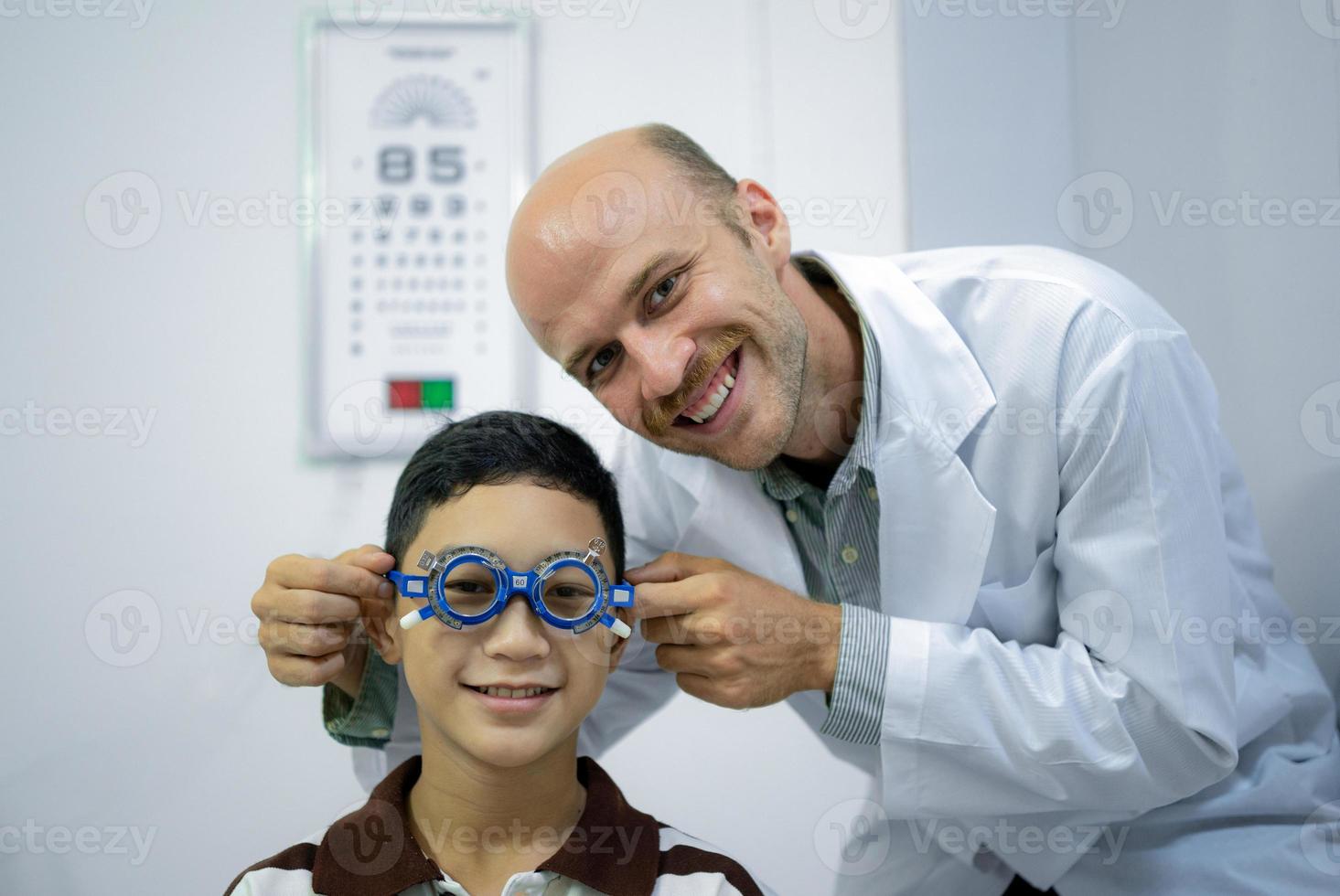 Boy has his eyes checked for glasses by a specialist. photo