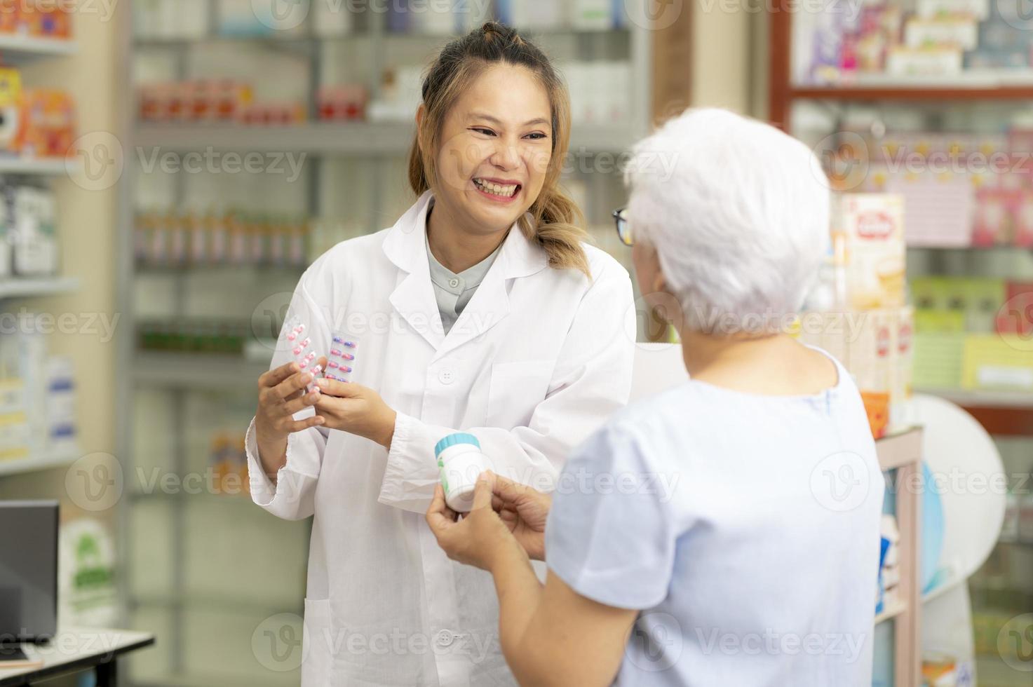 Asian female pharmacist gives indian elderly woman medicine advice to cure ailments. photo