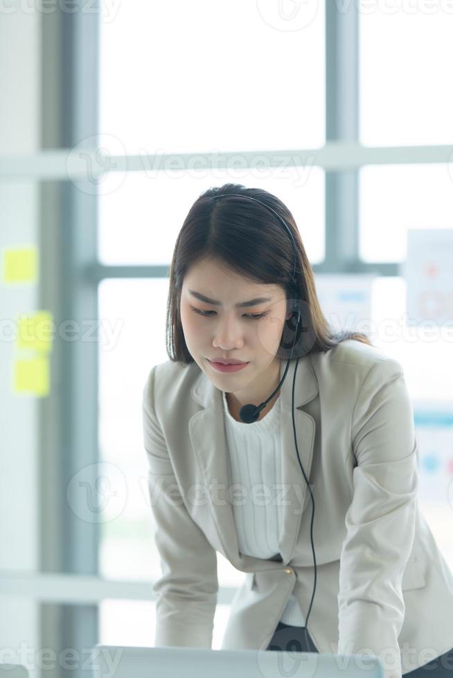 Young asian woman working at a call center Consulting about stock investment information with customers calling for advice with emotion of serious photo