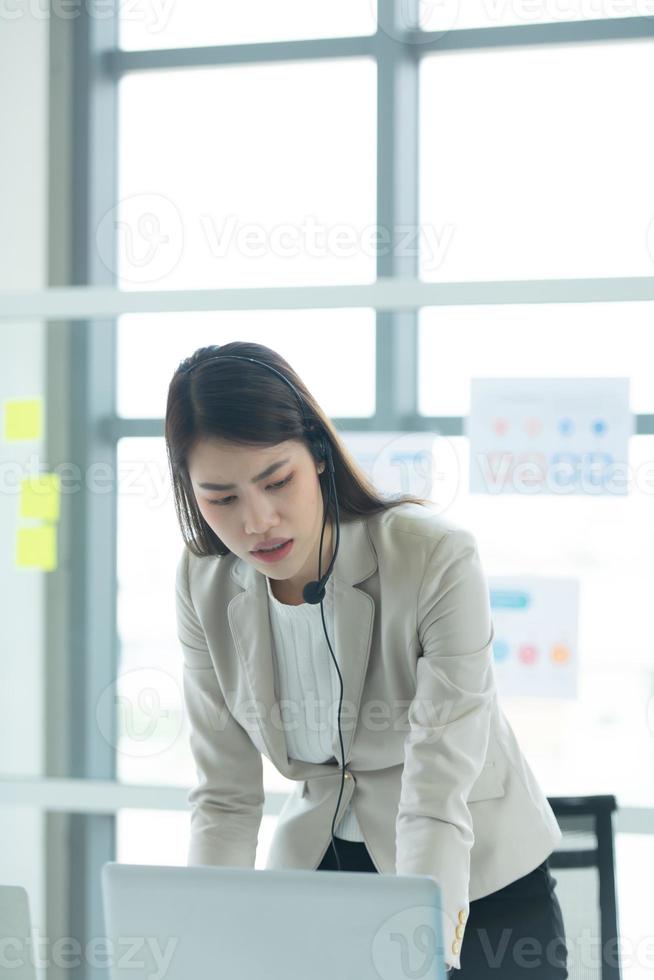 Young asian woman working at a call center Consulting about stock investment information with customers calling for advice with emotion of serious photo