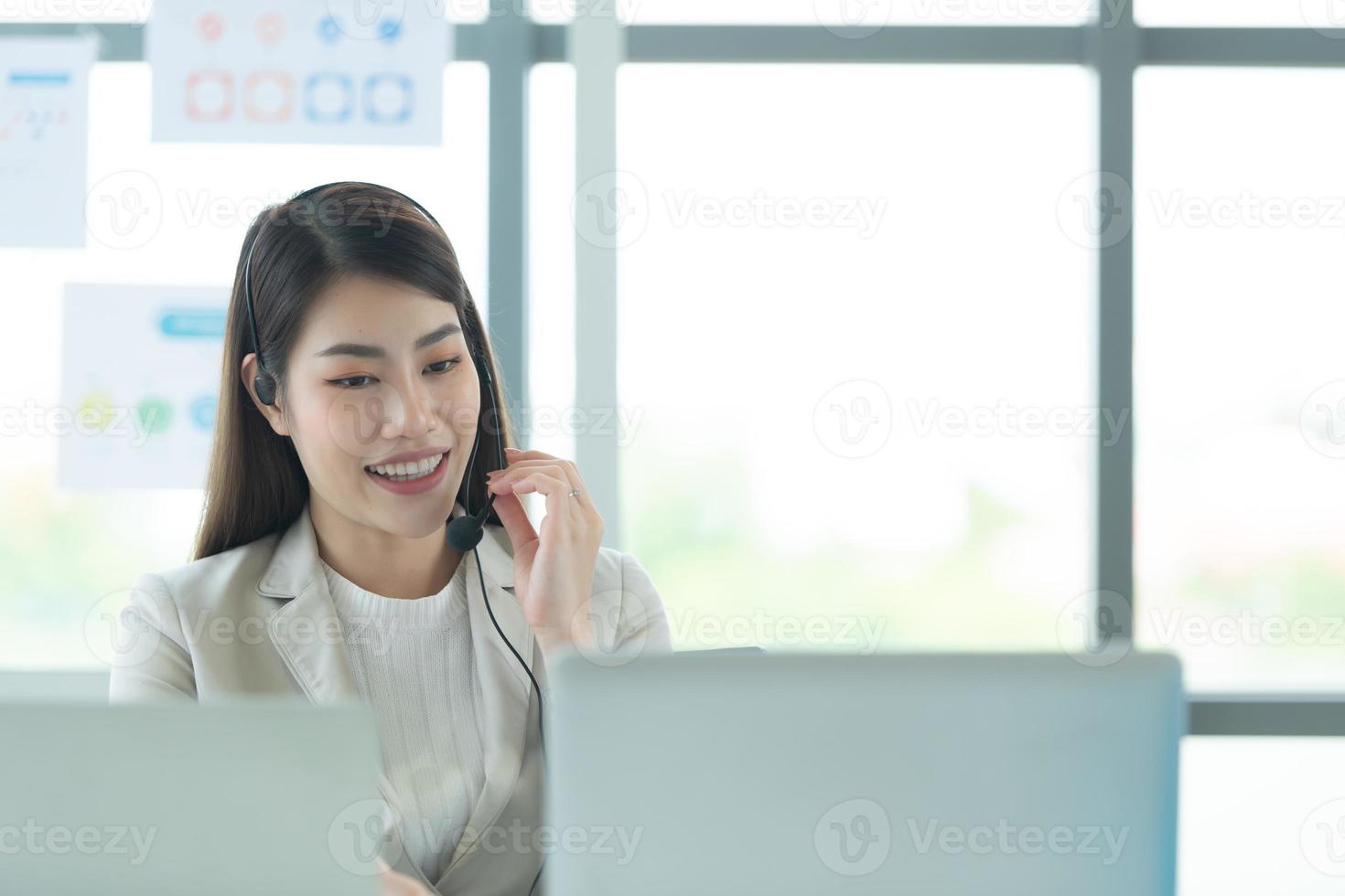 joven asiática que trabaja en un centro de llamadas consultando información sobre inversiones en acciones con clientes que piden consejo foto