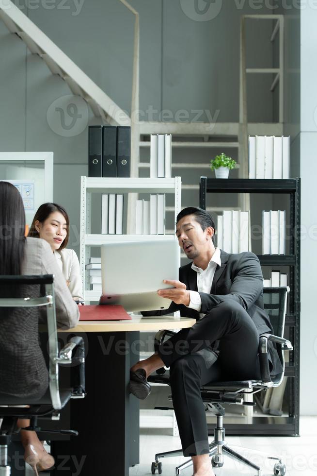 A group of young Asian entrepreneurs. Top Management is meeting to review stock investment data from the team in a meeting room with natural light photo