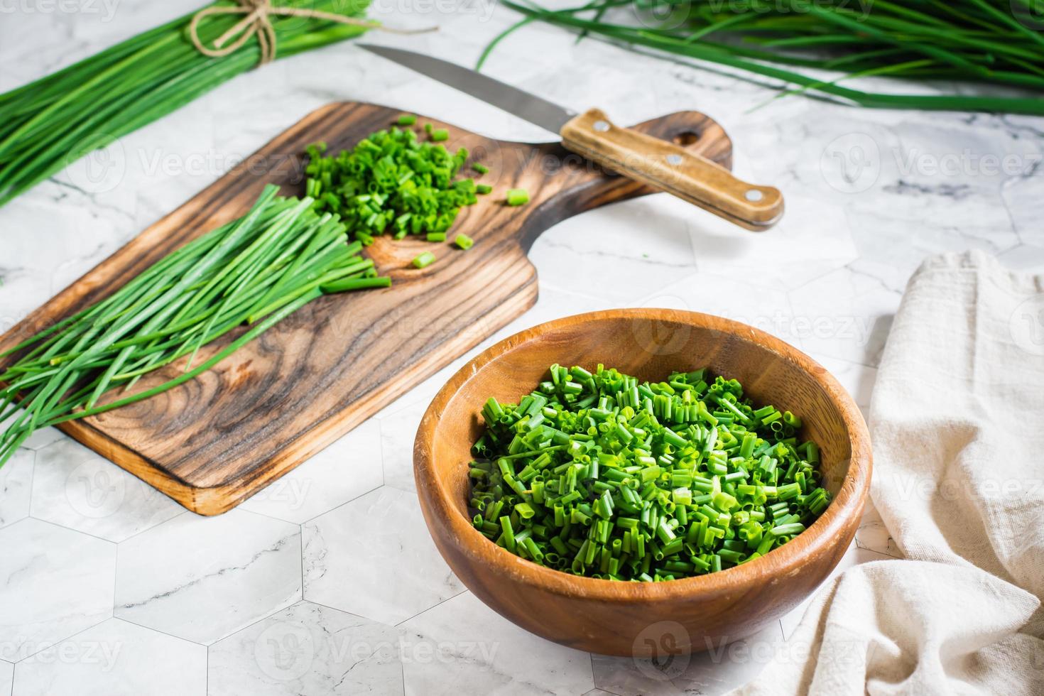 Fresh chopped green onions in a wooden bowl and a cutting board on the table. Vitamin herbal diet photo