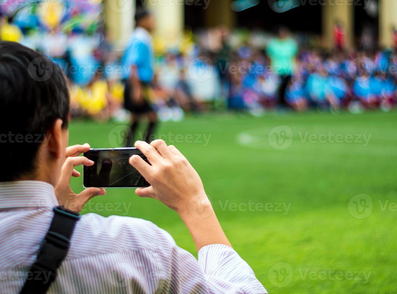 Man in work uniform Watch and shoot football competitions beside football field photo