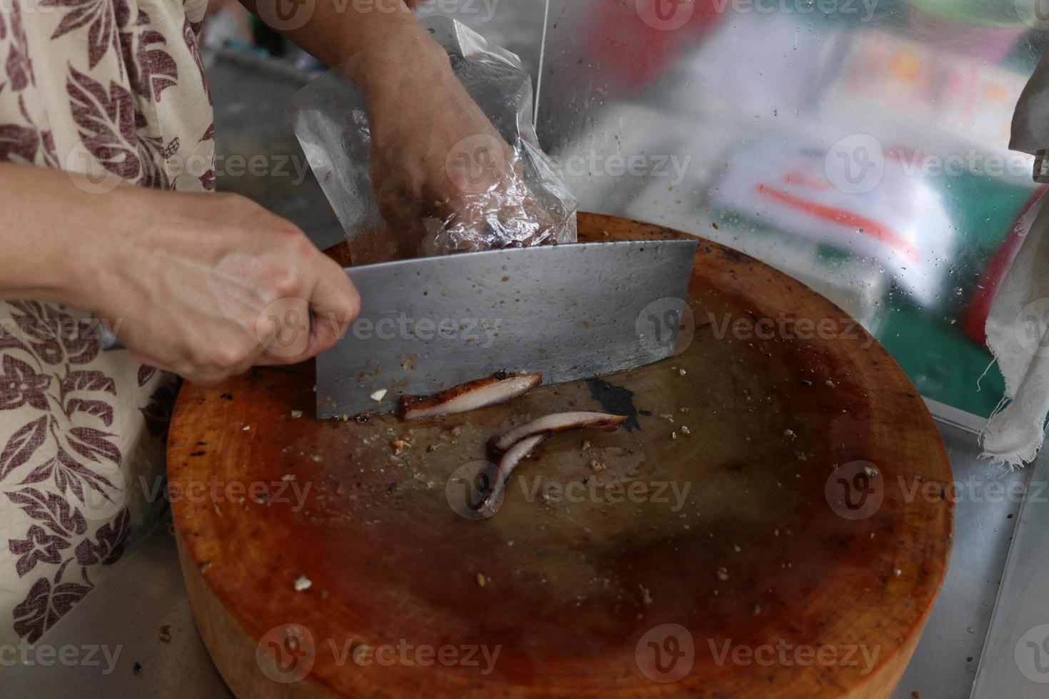 Hands are cutting roasted pork on circle wood broad, Thailand. photo