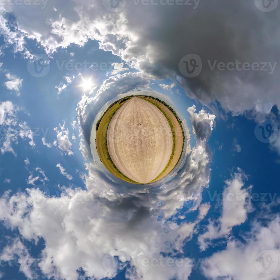 tiny planet in blue overcast sky with beautiful clouds with transformation of spherical panorama 360 degrees. Spherical abstract aerial view. Curvature of space. photo