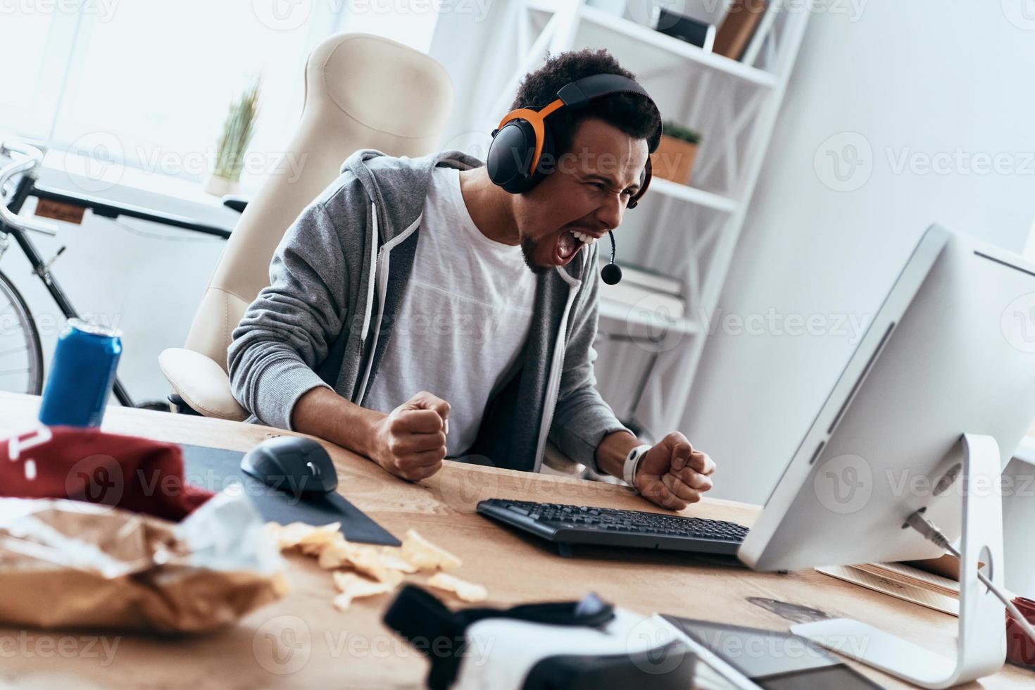 So angry Furious young man in casual clothing using computer and shouting while spending time at home photo