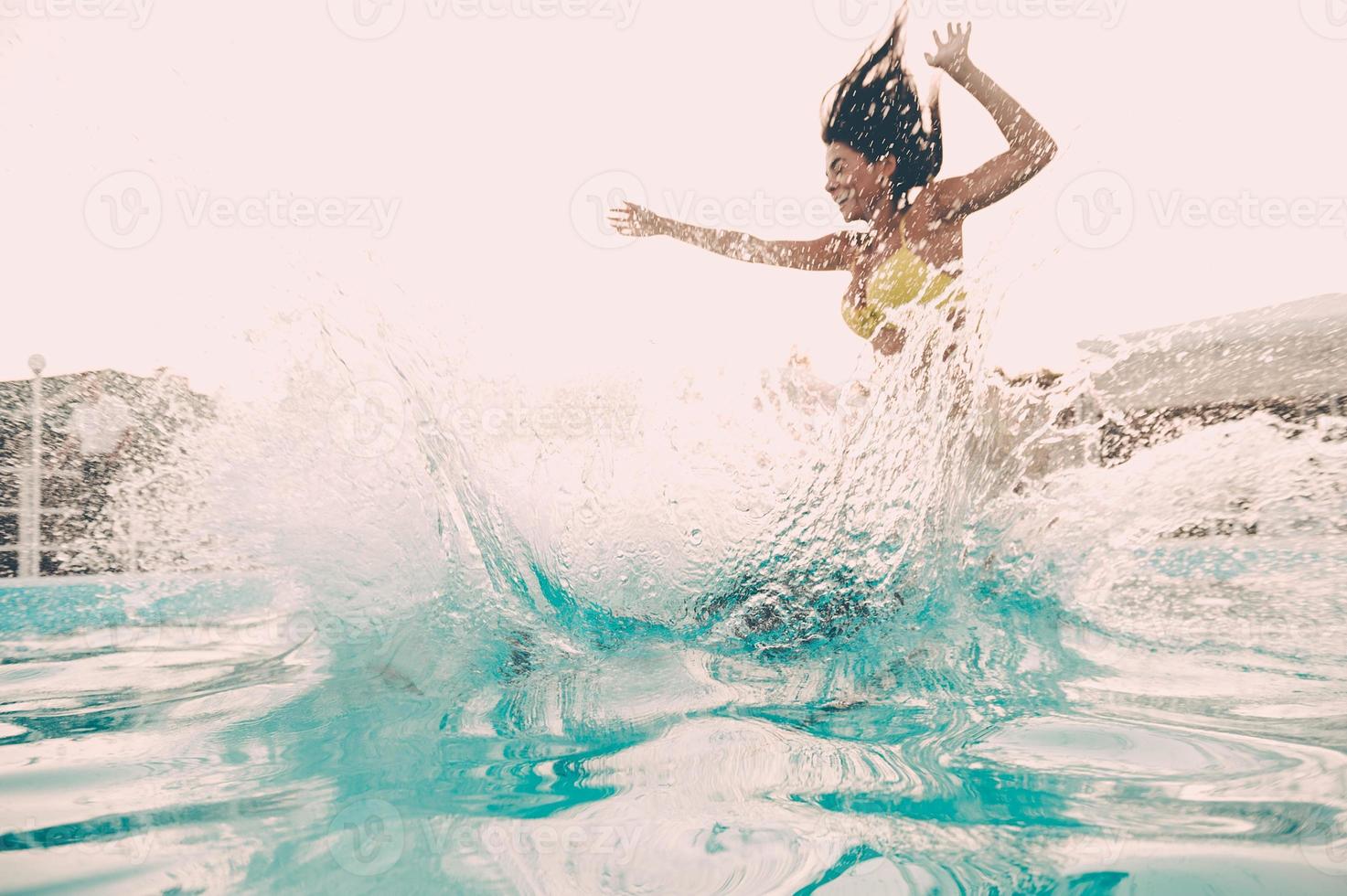 Pool fun. Beautiful young woman jumping into the outdoor swimming pool photo