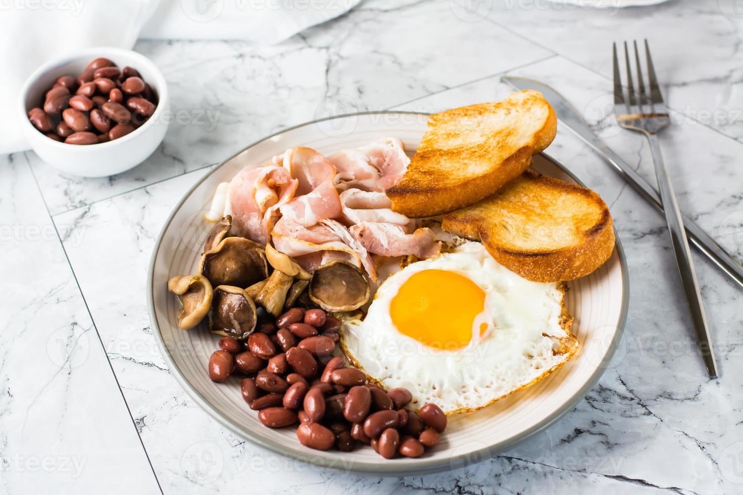 Traditional English breakfast with egg, bacon, beans, mushrooms and toast on a plate. photo