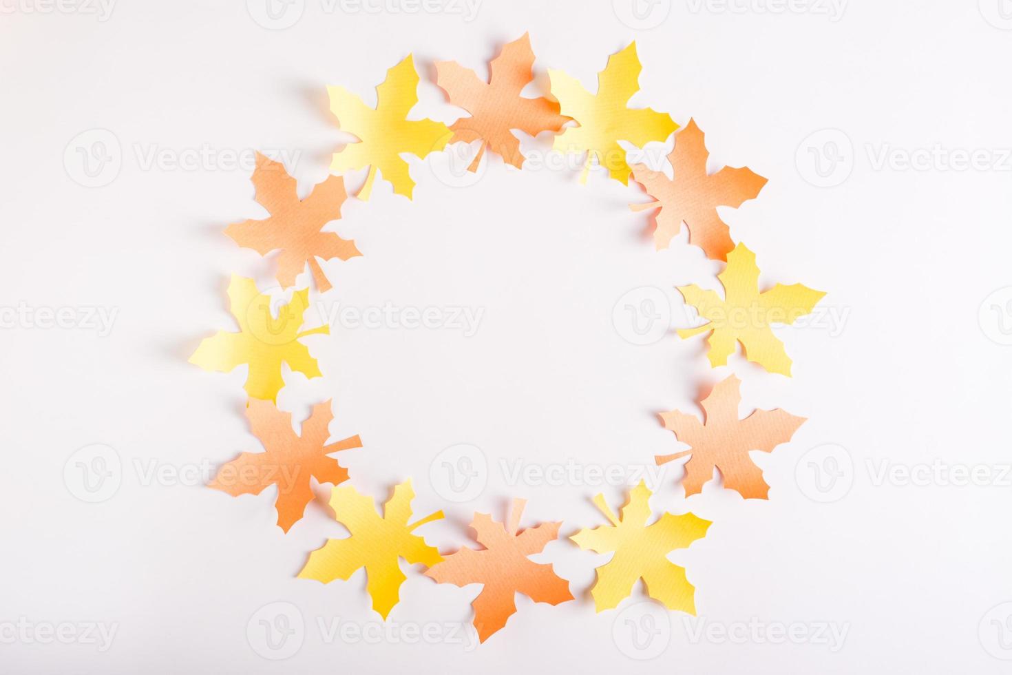 A wreath of paper maple leaves on a pink background. Top view. photo